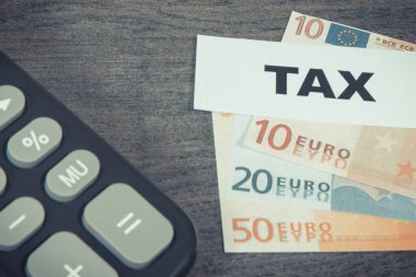 Hesap makinesi, yazıt vergisi ve euro banknotları. Hesaplama ve vergi ödeme. Ahşap arkaplan