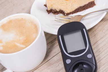 Glikoz ölçer, bir parça tatlı cheesecake ve sütlü bir fincan kahve. Diyabet sırasında şeker seviyesini ölçmek ve kontrol etmek