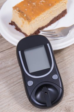 Glikoz ölçer ve bir parça tatlı cheesecake. Diyabet sırasında şeker seviyesini ölçmek ve kontrol etmek