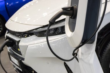 Poznan, Polonya - 5 Nisan 2024: Poznan Motor Fuarı. Yeni beyaz elektrikli Honda e: NY1 şarj istasyonuna bağlandı. Elektrikli aracı şarj etme işlemi. Elektrohareketliliğin gelişimi