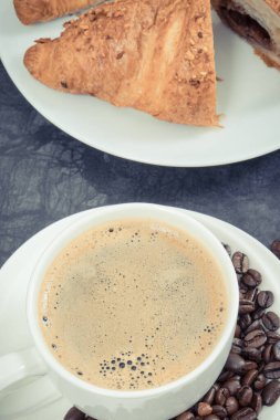 Taze pişmiş kruvasan, çikolatalı ve beyaz cam bardakta kahveden oluşan kahvaltı.