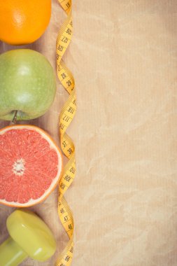 Taze olgun meyveler, mezura ve spor için kullanılan dambıllar. Sağlıklı bir yaşam tarzı. Kaynak mineraller ve vitaminler olarak meyveler. Metin veya yazı için yer