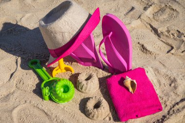 Aksesuarlar ve çocuklar kumsalda oynamak ya da dinlenmek için oyuncaklar. Hasır şapka, pembe terlik ve havlu. Yaz ve tatil zamanı