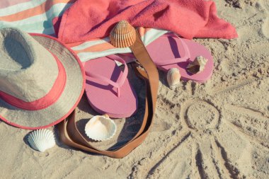 Kumda dinlenmek için güneş ve aksesuar şekli. Hasır şapka, pembe terlikler ve kabarık havlu. Kumsalda tatil zamanı.