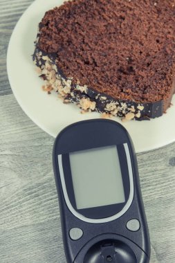 Glikoz ölçer ve tatlı çikolatalı pasta. Diyabet sırasında şeker seviyesini ölçmek ve kontrol etmek