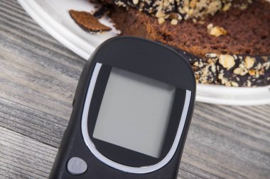 Glikoz ölçer ve tatlı çikolatalı pasta. Diyabet sırasında şeker seviyesini ölçmek ve kontrol etmek