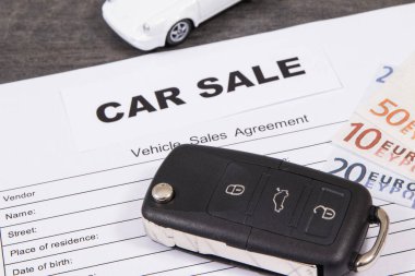 Küçük beyaz oyuncak araba, siyah araba anahtarı, euro banknotları ve araç satış anlaşması. Araba satışı. Araba satışı ya da alımları. Ulaşım