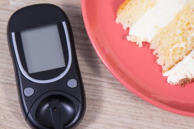 Şeker seviyesini ölçmek için glikoz ölçer ve çikolatalı bir parça tatlı kek. Diyabet konsepti sırasında sağlıklı yaşam tarzı