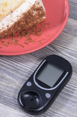 Şeker seviyesini ölçmek için glikoz ölçer ve çikolatalı bir parça tatlı kek. Diyabet konsepti sırasında sağlıklı yaşam tarzı