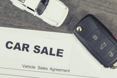 Küçük beyaz oyuncak araba, siyah araba anahtarı ve araç satış sözleşmesi. Araba satışı. Araba satışı ya da alımları. Ulaşım