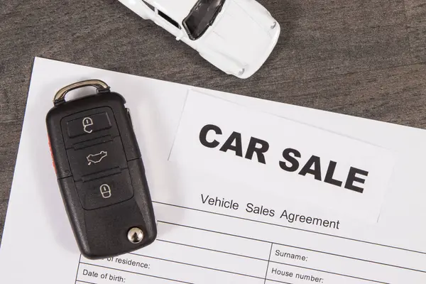 Küçük beyaz oyuncak araba, siyah araba anahtarı ve bir çeşit araç satış anlaşması. Araba satışı. Satışlar ya da alımlar yeni ya da kullanılmış araçlar. Ulaşım
