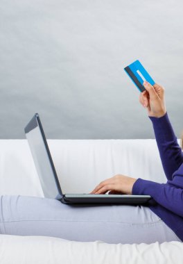 Kredi kartı ve dizüstü bilgisayarı olan bir kadın eli. İnternetten alışveriş için ödeme yapmak. Modern teknoloji
