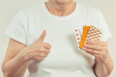 Elinde tablet ya da takviye malzemelerle yaşlı bir kadın. Tedavi ya da yaşlılıkta bağışıklığın güçlendirilmesi. Sağlık hizmetleri