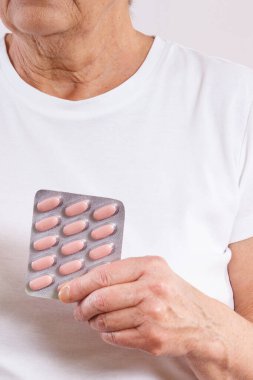 Elinde tablet ya da takviye malzemelerle yaşlı bir kadın. Tedavi ya da yaşlılıkta bağışıklığın güçlendirilmesi. Sağlık hizmetleri