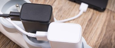 Siyah akıllı telefon, cep telefonu ve elektrik hattına bağlı şarj cihazları. Çeşitli aygıtlar şarj etme kavramı