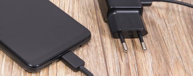 Siyah akıllı telefon, şarjlı cep telefonu. Çeşitli aygıtlar şarj etme kavramı