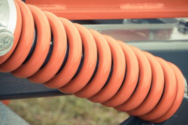 Çelikten yapılmış kırmızı sert yay. Detay ve büyük endüstriyel ya da tarımsal makinenin bir parçası. Teknoloji