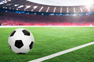 Seyirci ve güneş ışığıyla aydınlatılmış hayali bir stadyumda futbol. Arka planda sığ alan derinliğine sahip ön plandaki futbol topuna odaklan ve boşluğu kopyala.