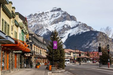 BANFF, CANADA - 22 Şubat 2024: Banff Ulusal Parkı 'ndaki Banff Bulvarı' nda arka planda Cascade Dağı var. Kasaba, dağlık çevresi ve kaplıcalarıyla ünlü büyük bir Kanada turizm beldesi..