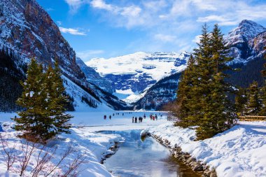 Frozen Lake Louise in the winter against the backdrop of the stunning Victoria Glacier. The iconic Lake Louise typically freezes from November to mid-April and draws visitors from all over the world during Winter. clipart