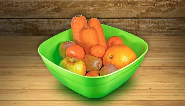 Ahşap masanın üzerinde meyve ve sebzeler olan yeşil plastik sepet.