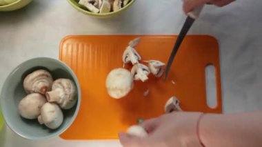 Profesyonel bir şefin elleri, taze şampiyon bir mantarı kesme tahtasıyla dilimlerken, yemek hazırlığını ön plana çıkarıyor.