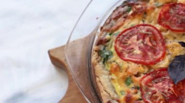 Kiş turtası, cam bir tabakta, üst manzara, ahşap bir kesme tahtasında.