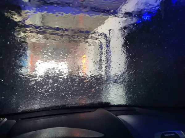 Automatic Car Wash Process. Spray foam bubble shampoo on the car surface. Car wash view from the salon