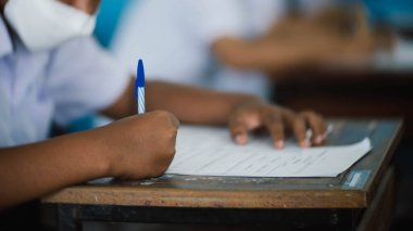 Koronavirüs acil durumu nedeniyle yüz maskesi takan öğrenci sınavına giriyor. Sınıfta oturan genç kadın Covid-19 salgınından dolayı cerrahi maske takıyor.