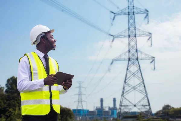 African engineer uses a tablet to operate a high-voltage power system from an electric power plant