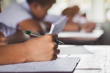 Sınav sorularını okuyan öğrenciler okul sınıfında baş ağrısıyla alıştırma yapıyorlar.