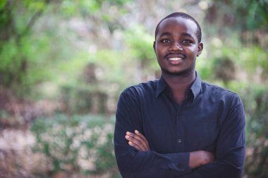 Afrikalı adam ellerini çapraz yapıp gülümsedi. Mutlu gülümseme ve olumlu düşünme kavramı.