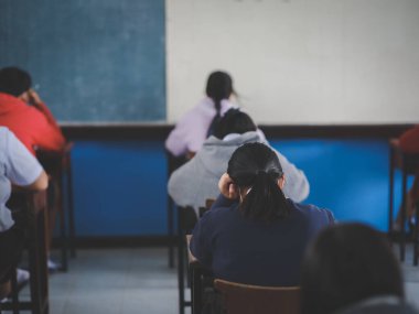 Sınav sorularını okuyan öğrenciler okul sınıfında baş ağrısıyla alıştırma yapıyorlar.