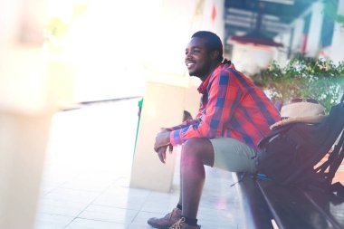 Afrikalı turist, sırt çantalı şapkalar ve güneş gözlükleriyle bir istasyonda tren bekliyor. Macera seyahati konsepti.