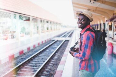 Şapka ve kamera takan Afrikalı gezginler bir istasyonda tren bekliyor. Macera seyahati konsepti.