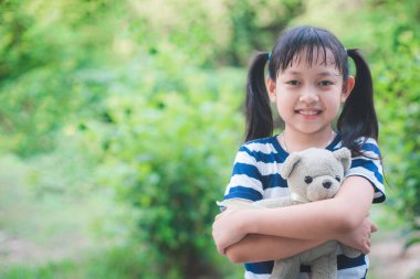 Mutlu çocuk oyuncak ayıyı yeşil doğada kucaklıyor. Zihinlerimizin kavramı önemlidir.