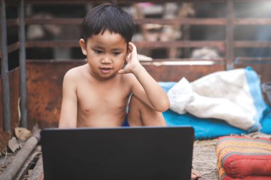 Asyalı küçük çocuk dizüstü bilgisayardan izliyor. Kırsal kesimdeki öğrenciler çevrimiçi öğrenim görüyorlar. Mutluluk yaşam tarzı kavramı