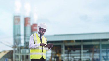 Beton fabrikasında çalışırken tablet kullanan Afrikalı mühendis