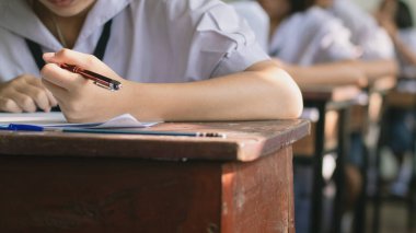 Üniformalı lise öğrencilerinin değerlendirme sınavı. Sınavları sınıfın içinde stresli bir şekilde yapıyorlardı.