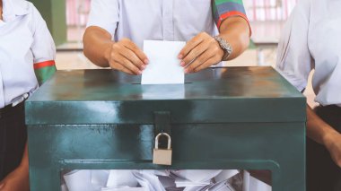 Öğrenciler oy pusulalarını bir kutuya koyuyorlar. Okul demokratik seçim kavramı.