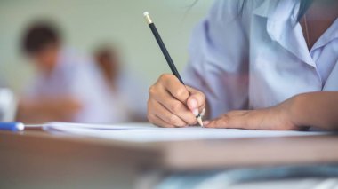 Üniformalı lise öğrencilerinin değerlendirme sınavı. Sınavları sınıfın içinde stresli bir şekilde yapıyorlardı.