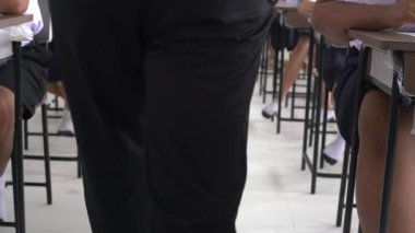 Öğretmen, öğrencilerin sınıfta sınava girmeleri için sınav odasını kontrol ediyor.