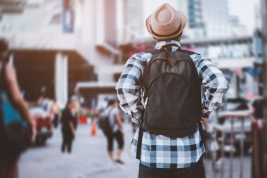 Afrikalı bir gezgin gökdelenleri ve arka planda yürüyen insanlarla modern bir başkente bakıyor.