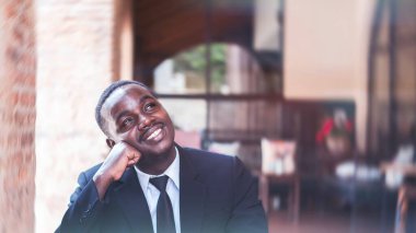 Siyah takım elbiseli Afrikalı işadamı umut dolu bir ifadeyle gelecekteki iş projesini düşünüyor..