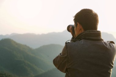 Akşamları dağın tepesinde durup güneşin batışını fotoğraflayan bir fotoğrafçı. Fotoğrafçılık ve macera yolculuğu fotoğrafçılığı kavramı.