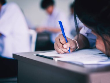 Üniformalı lise öğrencilerinin değerlendirme sınavı. Sınavları sınıfın içinde stresli bir şekilde yapıyorlardı.