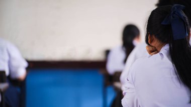 Öğrenciler sınav cevap kağıtlarını baş ağrısı ve stres ile birlikte okul sınıfında okuyorlar.