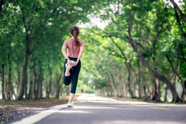 Koşucu kadın parkta koşmadan önce bacaklarını açıyor, sağlıklı yaşam tarzı ve spor kavramları, ısınma, kopyalama alanı.