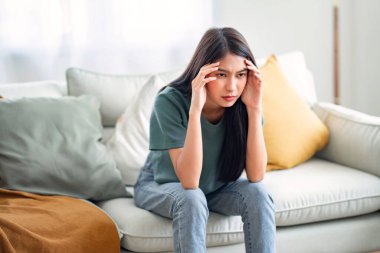 Üzgün, genç Asyalı kadın alnına dokunuyor. Baş ağrısı ya da depresyon geçiriyor. Sıkıntılı, sıkıntılı bir kız.