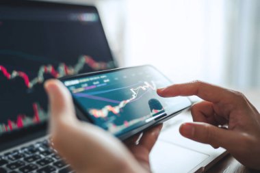 Yakın plan - Kadın akıllı telefon, kripto para birimi gelecekteki fiyat öngörüsünde Bitcoin fiyat tablosunu kontrol ediyor.